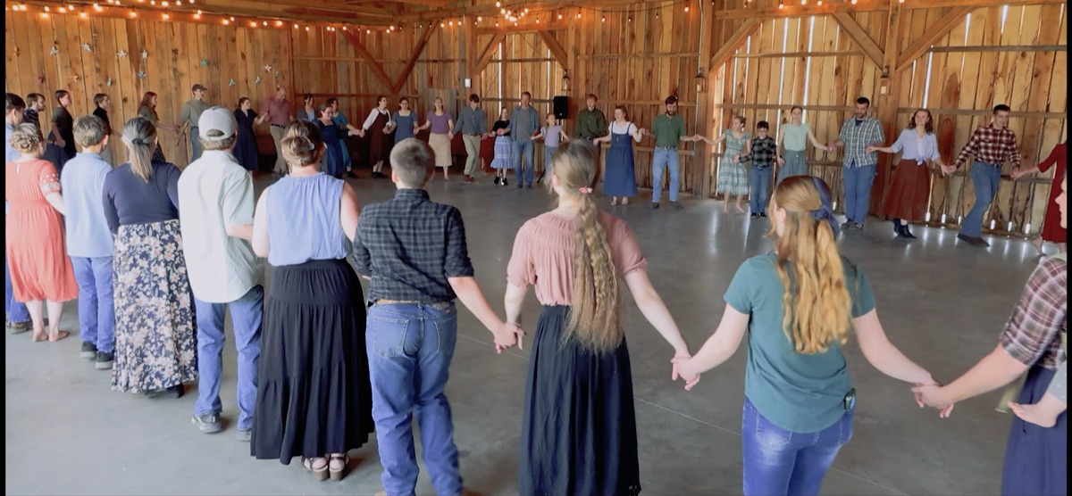 A large mixed-age circle holding hands during the German Waltz