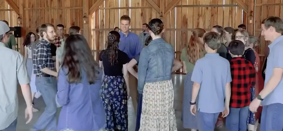 A mixed-age barn dance group gathering in a circle and smiling together